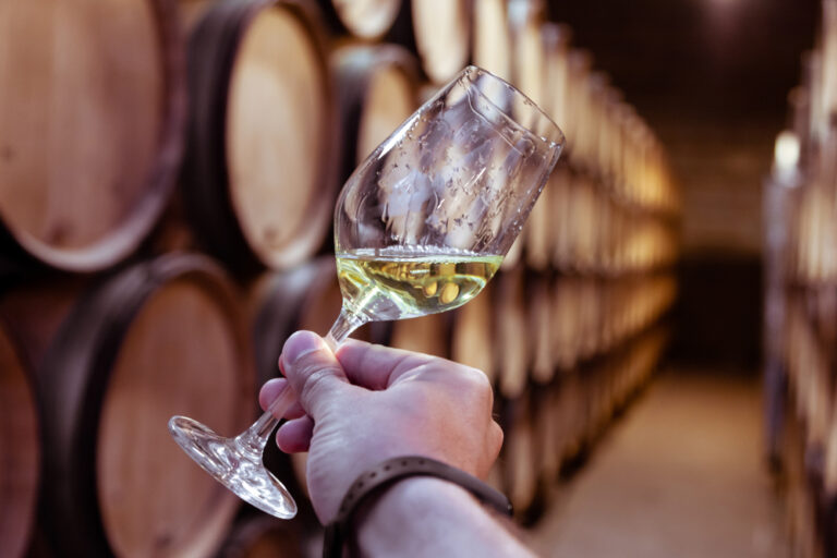 Closeup,Male,Hand,With,Glass,Of,White,Wine,On,Background