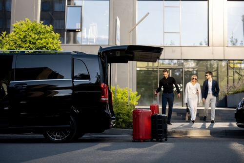 Driver,Or,Concierge,Helps,A,Business,Couple,Carry,Their,Suitcases